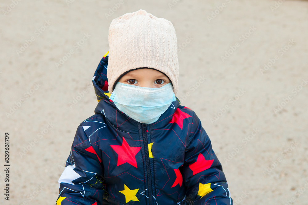 child, a boy in a medical mask on a walk near the house. walking with a child during the quarantine of the coronavirus pandemic. child, a boy in a medical mask on a walk near the house. walking with a child during the quarantine of the coronavirus pandemic.