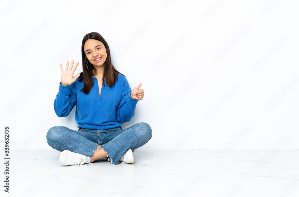 Young mixed race woman sitting on the floor isolated on white background counting six with fingers Young mixed race woman sitting on the floor isolated on white background counting six with fingers
