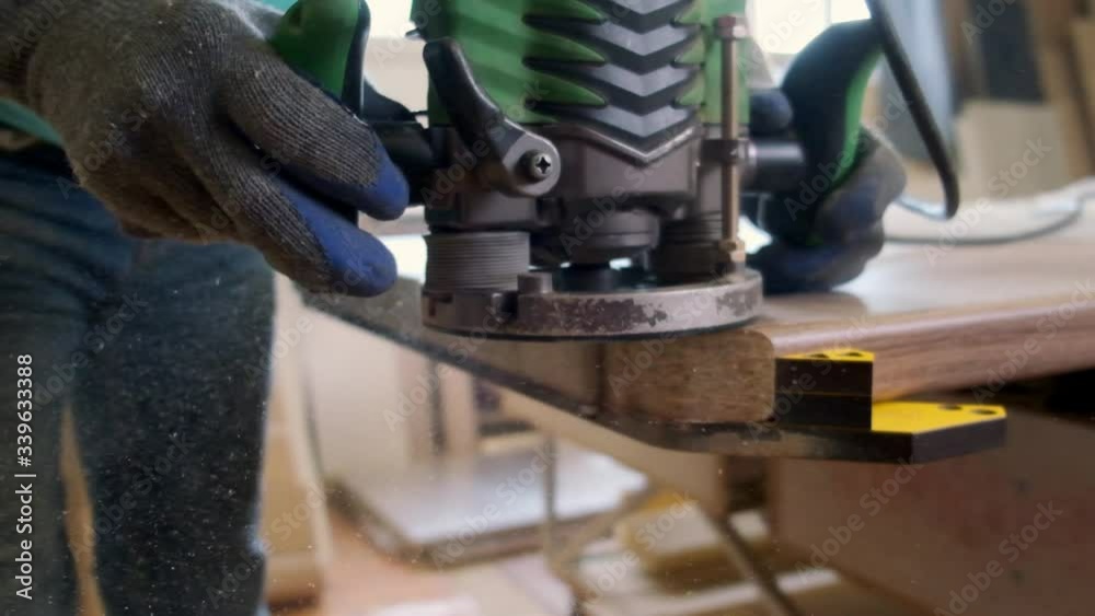 Professional carpenter makes furniture, levels the edge of the table with a milling machine in slow motion Professional carpenter makes furniture, levels the edge of the table with a milling machine in slow motion
