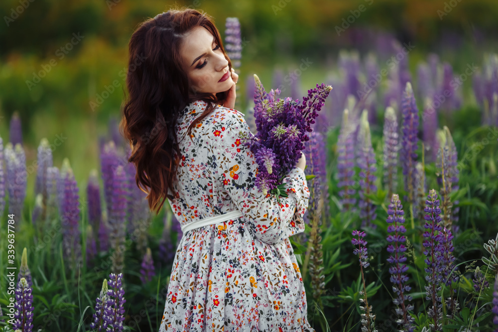 brunette in a flower field.The girl holds lupines purple. brunette in a flower field.The girl holds lupines purple.