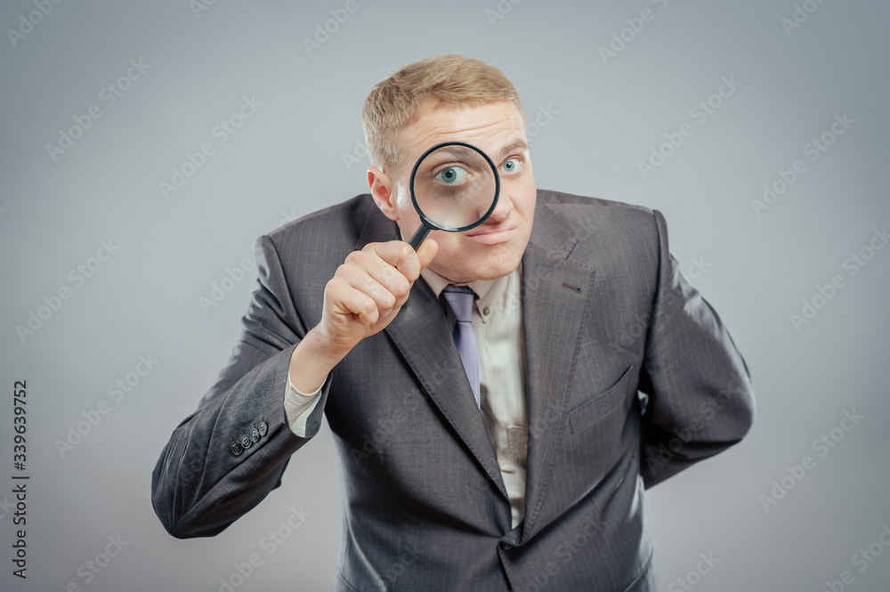 Funny image of a adult man with a magnifying glass, one eye is enlarged. Funny image of a adult man with a magnifying glass, one eye is enlarged.