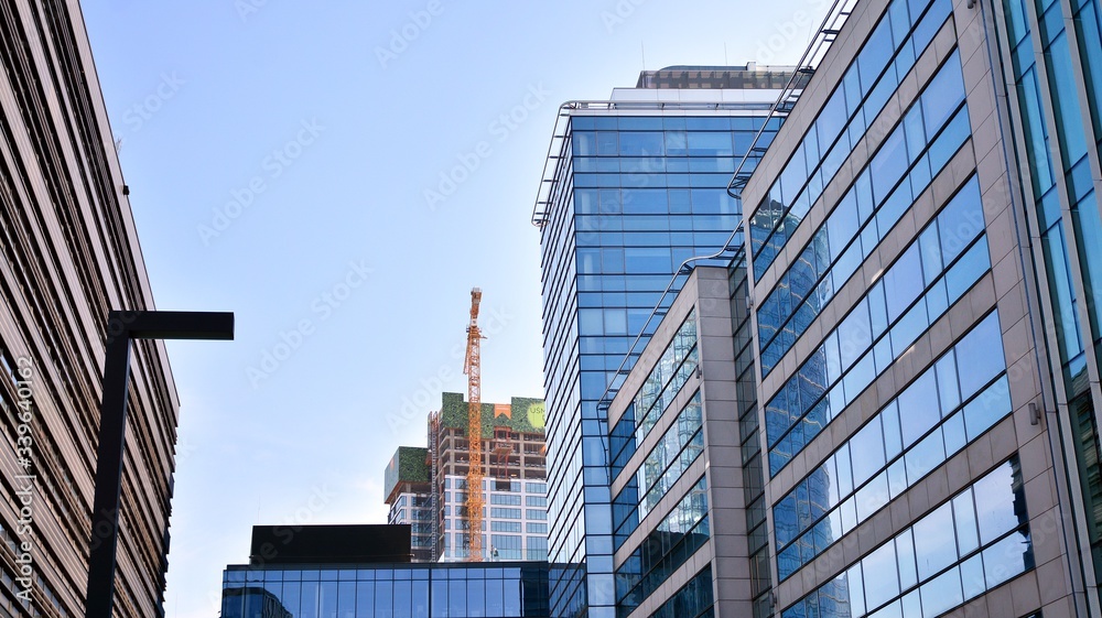 Naklejka premium Blue curtain wall made of toned glass and steel constructions under blue sky. A fragment of a building.