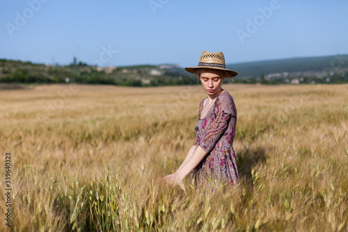 Portrait of a beautiful fashionable blonde woman in a dress and a field of wheat