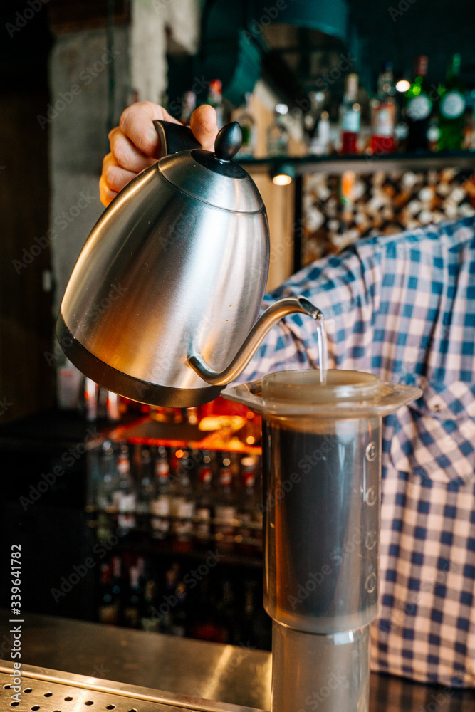 Alternative Coffee Brewing Method. Close-up of barista hand pouring water from the kettle to Chemex in the restaurant.