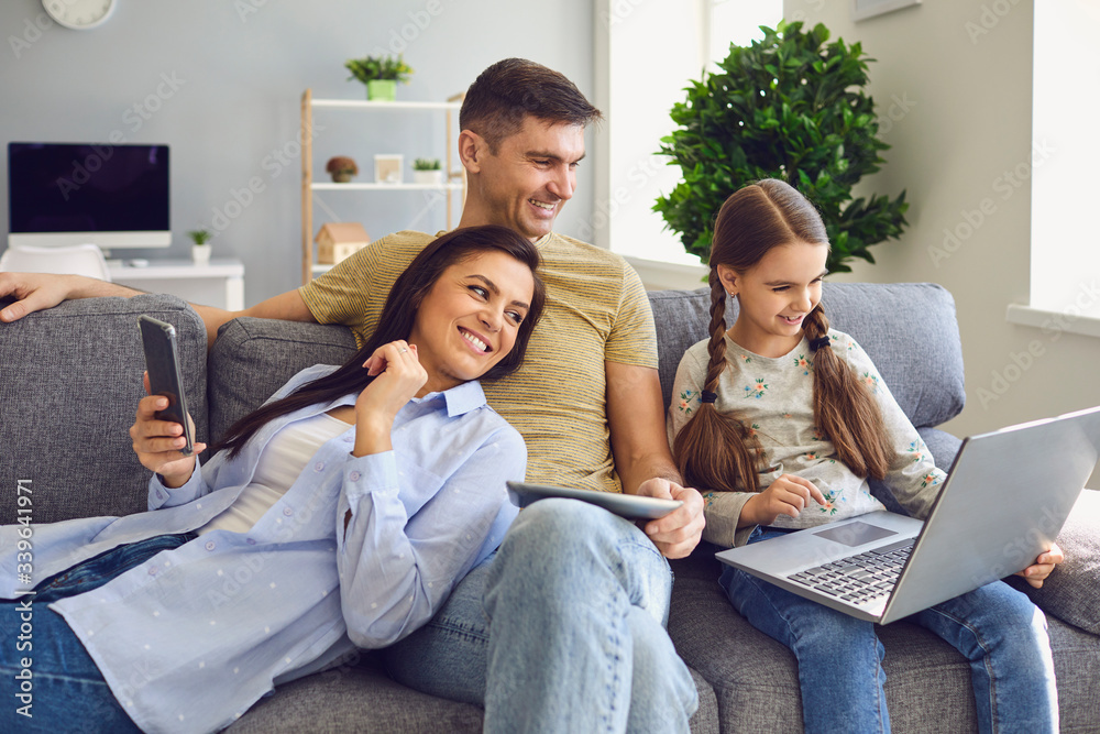 A happy family uses a laptop together while sitting at home. A happy family uses a laptop together while sitting at home.