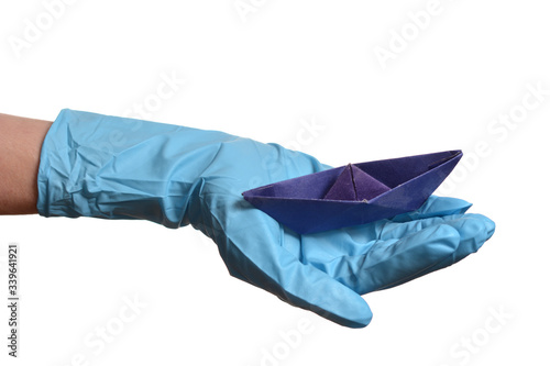 Origami paper boat in hand with rubber gloves over white