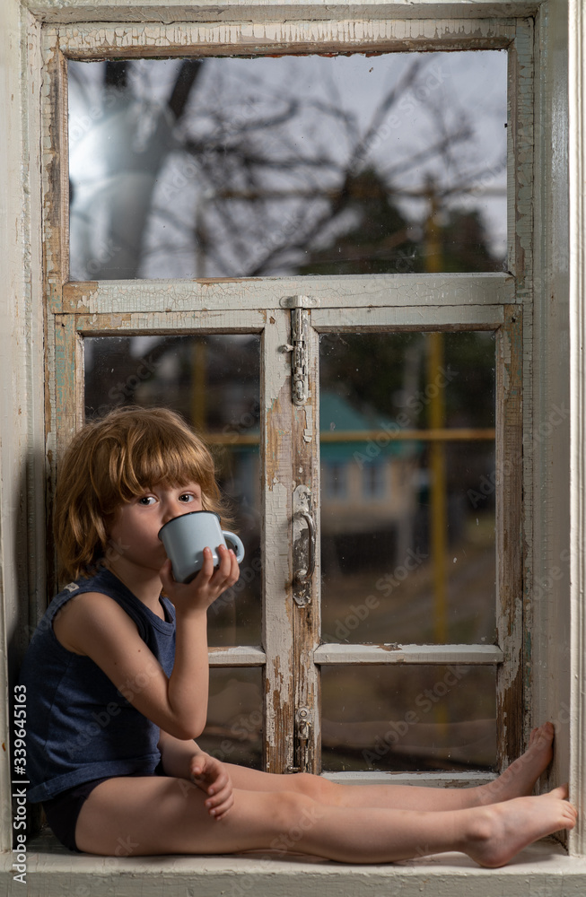 Obraz premium a boy with blond hair sits on a windowsill