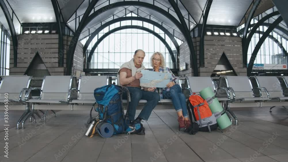 Senior couple studying map sitting in airport lunge area