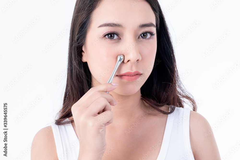Portrait images of Asian young, pretty woman is 25 years old, She is using stainless steel bars Massage the skin Nose area to help reduce wrinkles and tighten the skin, to beauty concept. Portrait images of Asian young, pretty woman is 25 years old, She is using stainless steel bars Massage the skin Nose area to help reduce wrinkles and tighten the skin, to beauty concept.