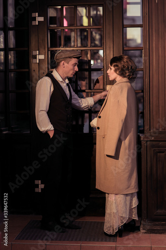 A young man and woman are standing against the background of a glass door, talking about something. Historical reconstruction