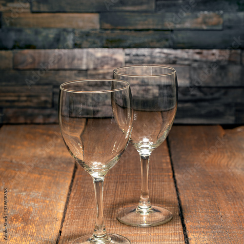 Pair of empty wine glasses against a rustic wood background.