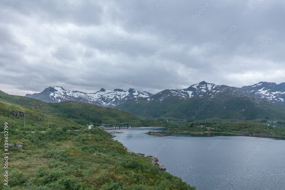 Norwegian fjord and mountains surrounded by clouds, midnight sun, polar day, ideal fjord reflection in clear water. selective focus. Norwegian fjord and mountains surrounded by clouds, midnight sun, polar day, ideal fjord reflection in clear water. selective focus.