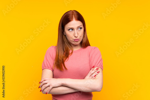 Young redhead woman over isolated yellow background thinking an idea