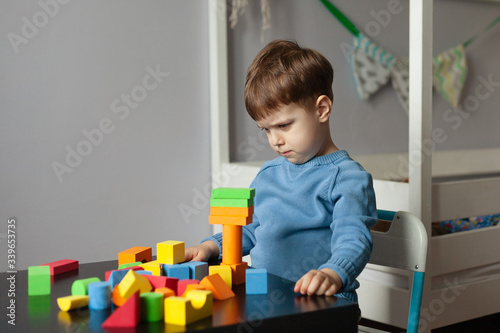 Creative boy playing with colorful cubes Little child playing at home. Educational games for preschool children