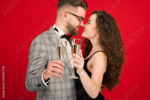Selective focus of couple holding glasses of champagne isolated on red background