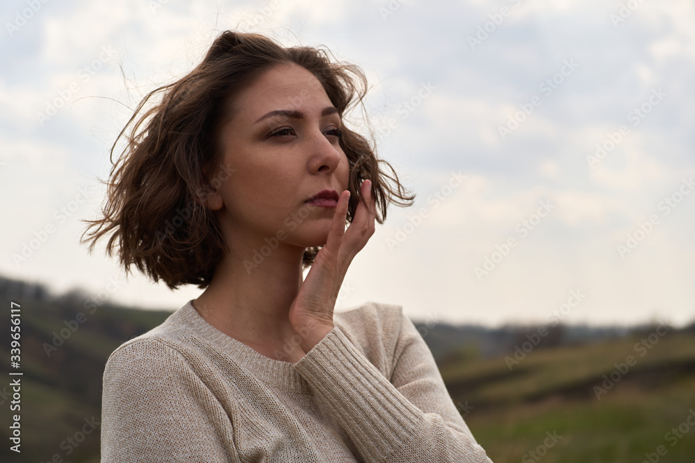 Portrait of beautiful girl on nature view background with hills and sky. Young woman is looking thoughtfully, isolated outdoor Portrait of beautiful girl on nature view background with hills and sky. Young woman is looking thoughtfully, isolated outdoor
