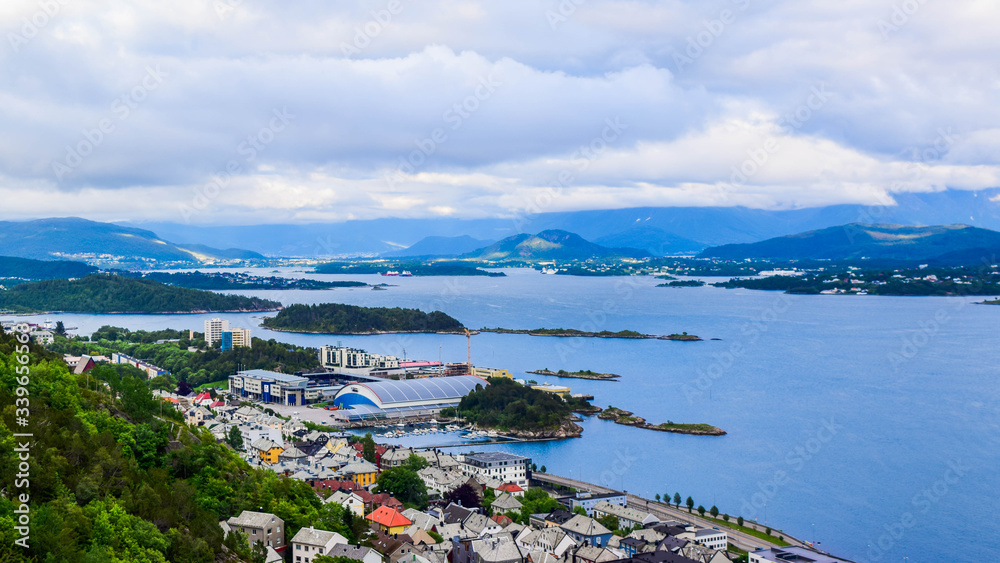 The beautiful sunset over Alesund cityscape. Neoclassical and neo-Gothic stone buildings. Art Nouveau architecture. Sun rays illuminate Atlantic Ocean and islands. View from Aksla viewpoint. Norway.