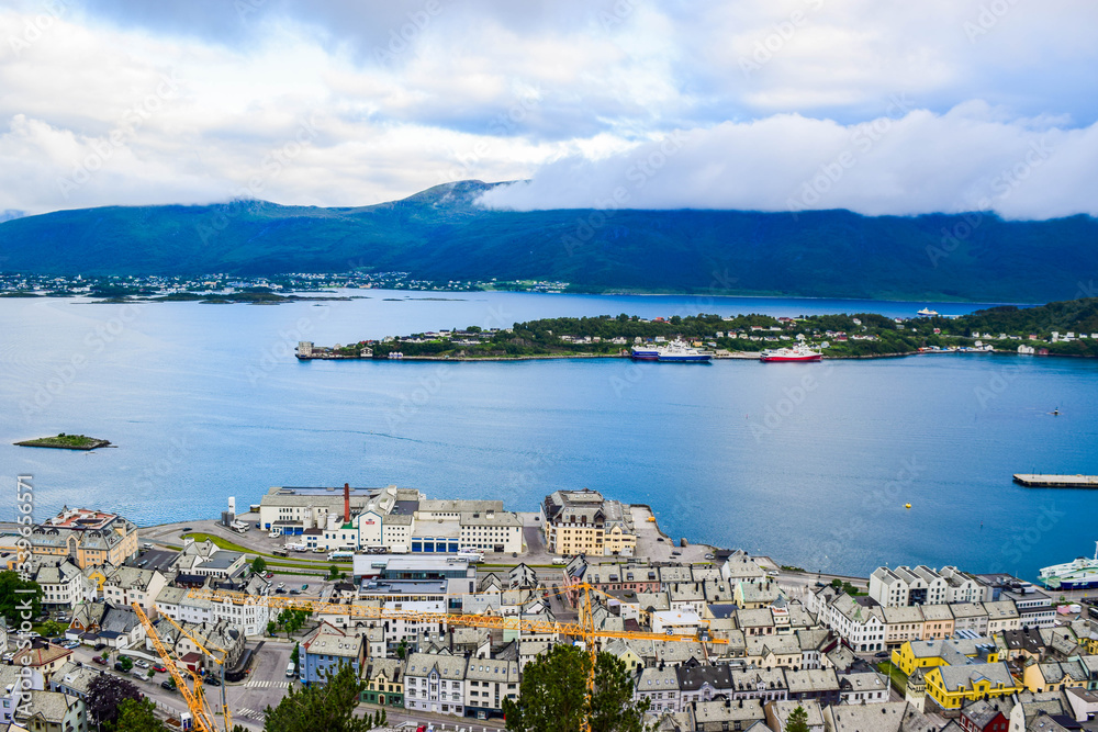 The beautiful sunset over Alesund cityscape. Neoclassical and neo-Gothic stone buildings. Art Nouveau architecture. Sun rays illuminate Atlantic Ocean and islands. View from Aksla viewpoint. Norway.
