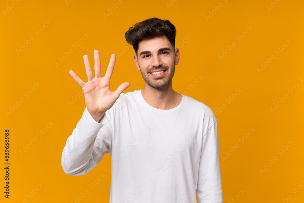 Young man over isolated orange background counting five with fingers Young man over isolated orange background counting five with fingers