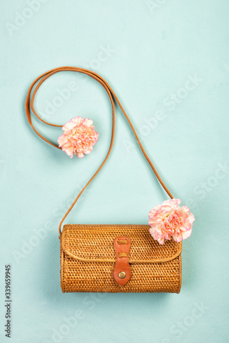 Summer Indonesian rattan eco bags and pink flowers on a turquoise canvas background. Top view, flat lay with copy space