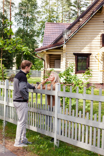 Middle aged man talking to his female neighbor over wooden fence on way home in countryside