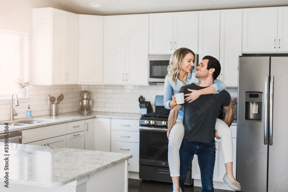 young married couple flirting in their clean kitchen young married couple flirting in their clean kitchen
