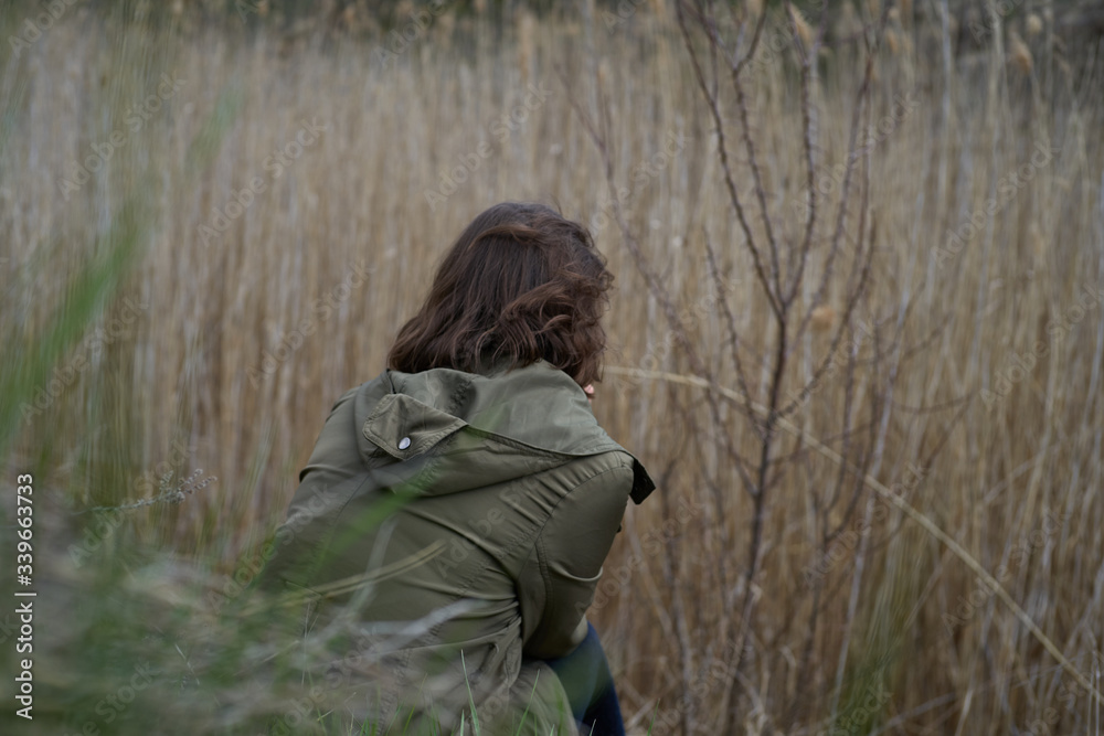 Alone girl sad in the canyon in the reeds. Young woman isolated outdoor, post apocalyptic, pandemic, adolescence, home violence, problems of teenagers, concept loneliness Alone girl sad in the canyon in the reeds. Young woman isolated outdoor, post apocalyptic, pandemic, adolescence, home violence, problems of teenagers, concept loneliness