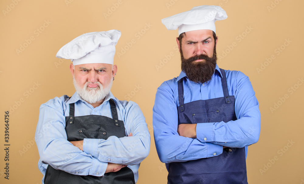 Restaurant kitchen. Culinary industry. Restaurant staff. Father and son culinary hobby. Mature bearded men professional restaurant cooks. Chef men wear aprons. Family restaurant. Cafe workers
