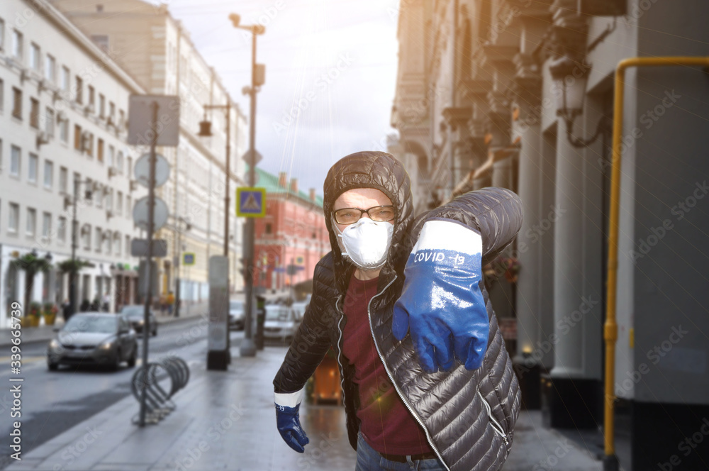 A man in a protective mask and gloves with the inscription COVID-19 against the backdrop of an urban environment. Coronavirus infection protection concept. COVID-19.
