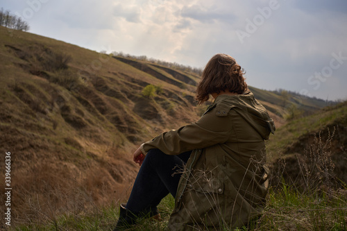 Alone girl on beautiful mountain view feeling free with wind  and sky. Isolated woman on nature background, freedom, post apocalypse