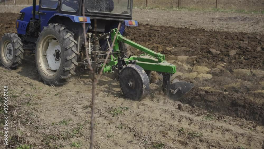 Close up Tractor cultivates the land for planting of the earth. planting vegetables for food Close up Tractor cultivates the land for planting of the earth. planting vegetables for food