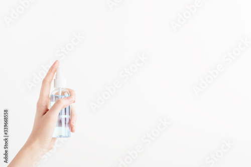 Transparent container for sterilizer products with dispenser. Female hand pushing on unbranded plastic bottle with disinfector. Mockup style, copy space. Health and hygiene concept. Isolated on white