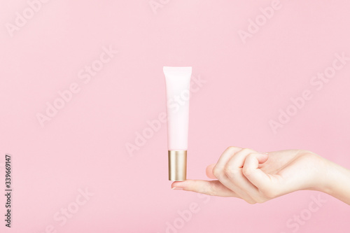 Wallpaper Mural Unbranded flacon on female finger. Plastic tube for cream,body lotion, toiletry. Container for professional cosmetics product. Skincare and beauty concept. Mockup, copy space. Isolated on pink. Torontodigital.ca