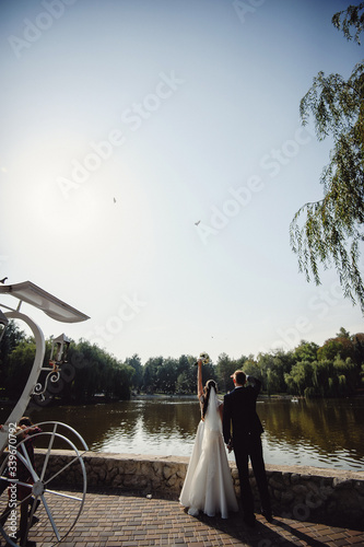 The fiance in black tuxedo and the bride in a white dress let go pigeons. View from behind. Morning Bride. Wedding fato sesia. Vertical photo photo