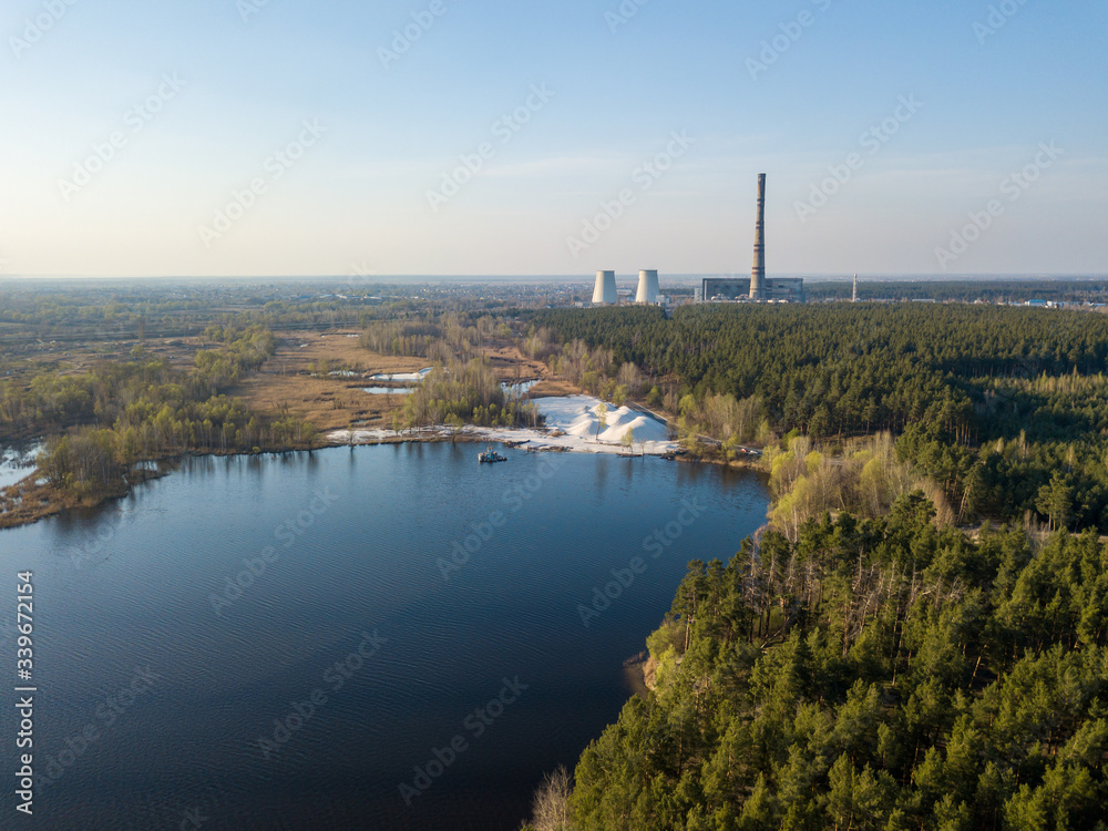 A lake in a coniferous forest on the outskirts of a city. Aerial drone view.