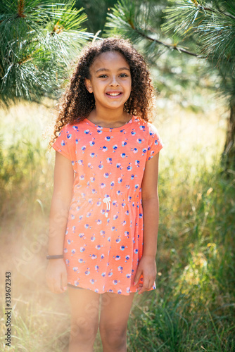 Portrait of smiling curly haired girl outside in nature
