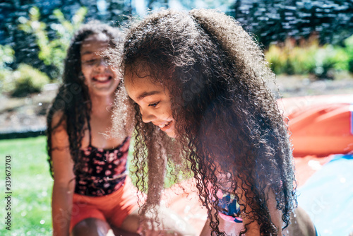 Girls playing on slip and slide in front yard of home