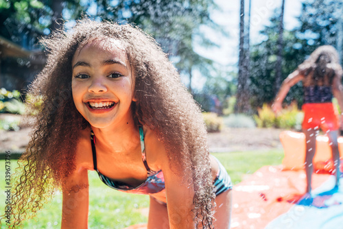 Girls playing on slip and slide in front yard of home photo