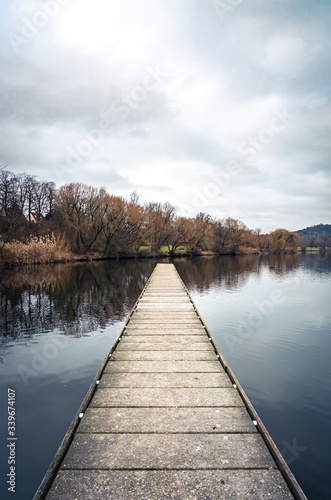 Targeted wooden jetty on a calm lake on a cloudy day in Germany; purposeful, symmetrical, centered