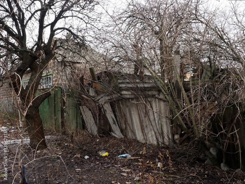 Old country house in the village in spring. Crumbling old village house in bad weather photo