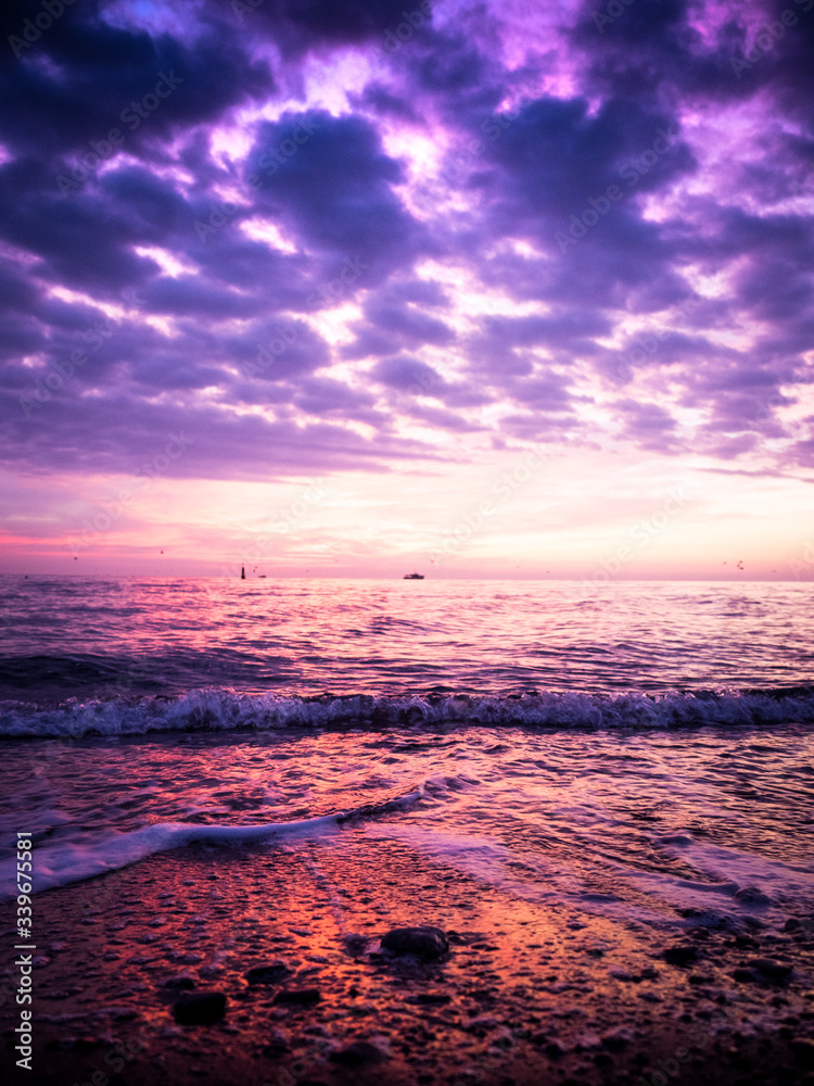 Wonderful view of the sunrise on the sea coast with colored clouds