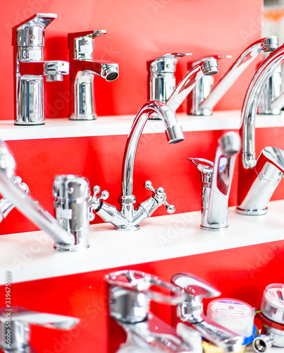 In the construction store in the plumbing department, there are beautiful taps for the bathroom and kitchen against a red background Belarus, Minsk, April 11, 2020.