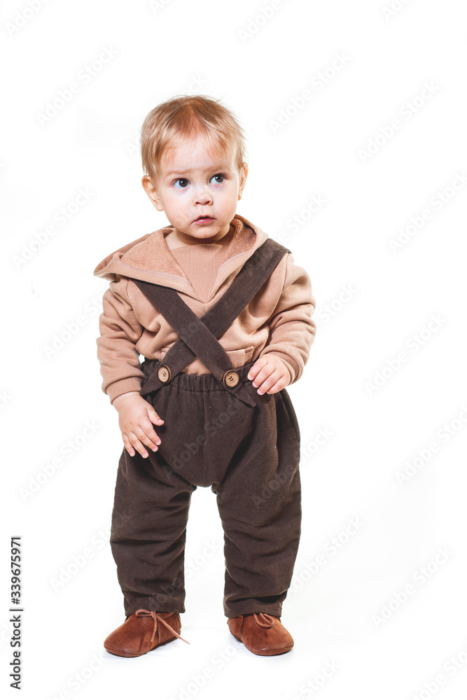 portrait of a charming one-year-old little boy on a white background, dressed in brown trousers, a beige hoodie, portrait of a charming one-year-old little boy on a white background, dressed in brown trousers, a beige hoodie,