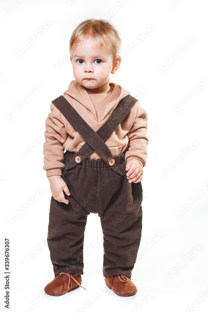 portrait of a charming one-year-old little boy on a white background, dressed in brown trousers, a beige hoodie, portrait of a charming one-year-old little boy on a white background, dressed in brown trousers, a beige hoodie,