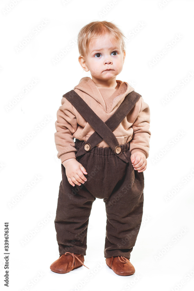 portrait of a charming one-year-old little boy on a white background, dressed in brown trousers, a beige hoodie, portrait of a charming one-year-old little boy on a white background, dressed in brown trousers, a beige hoodie,