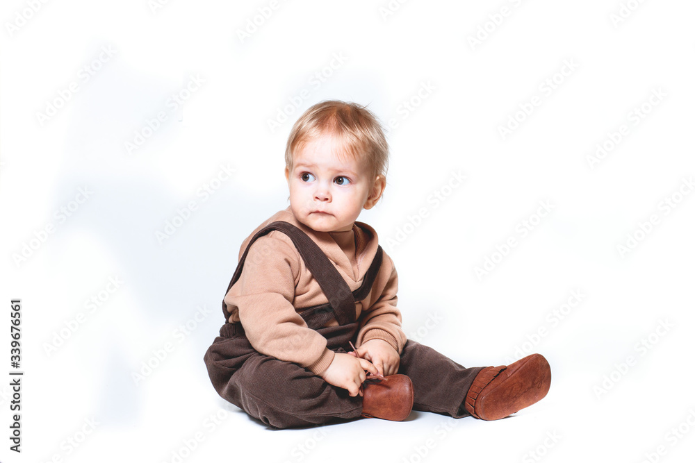 portrait of a charming one-year-old little boy on a white background, dressed in brown trousers, a beige hoodie, portrait of a charming one-year-old little boy on a white background, dressed in brown trousers, a beige hoodie,