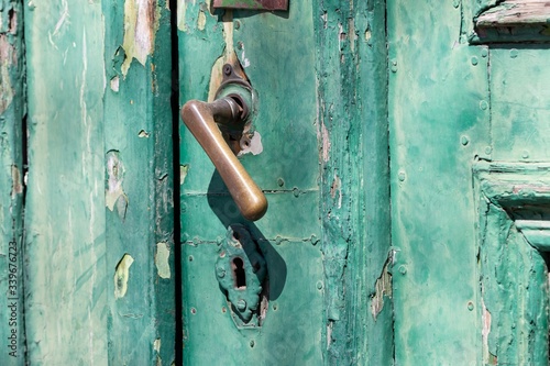 Large metal handle on a green old wooden door, design of hardwar