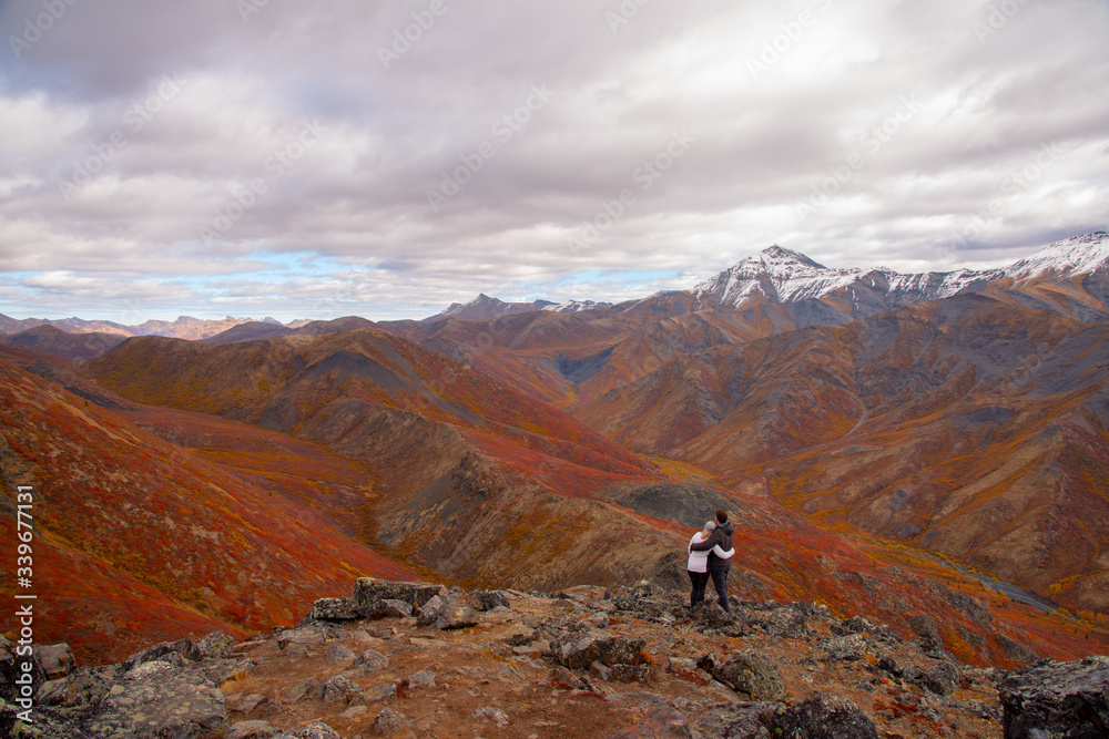 The mountains of Tombstone Territorial Park in Northern Canada, Yukon Territory taken in the fall autumn, just as the first snowfall appeared on the mountain tops. Couple hugging on mountain peak. 