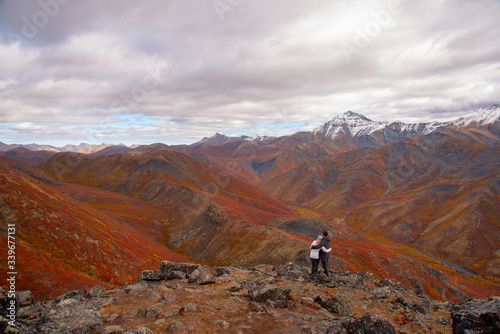 The mountains of Tombstone Territorial Park in Northern Canada, Yukon Territory taken in the fall autumn, just as the first snowfall appeared on the mountain tops. Couple hugging on mountain peak. 