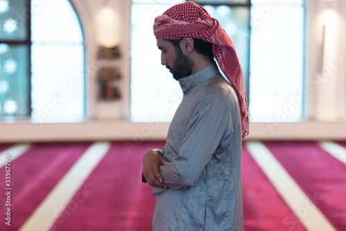 Young Arabic Muslim man  praying. Doing a dailly pray inside modern beautiful mosque. photo